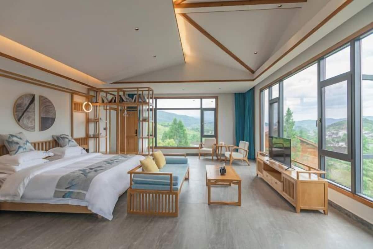 Une chambre d’hôtel moderne, dotée d’un grand lit, d’un canapé, d’une télévision et offrant une vue sur l’extérieur.