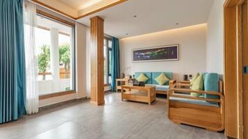 Amplia sala de estar con sofá, mesa de centro de madera y un ventanal con cortinas.