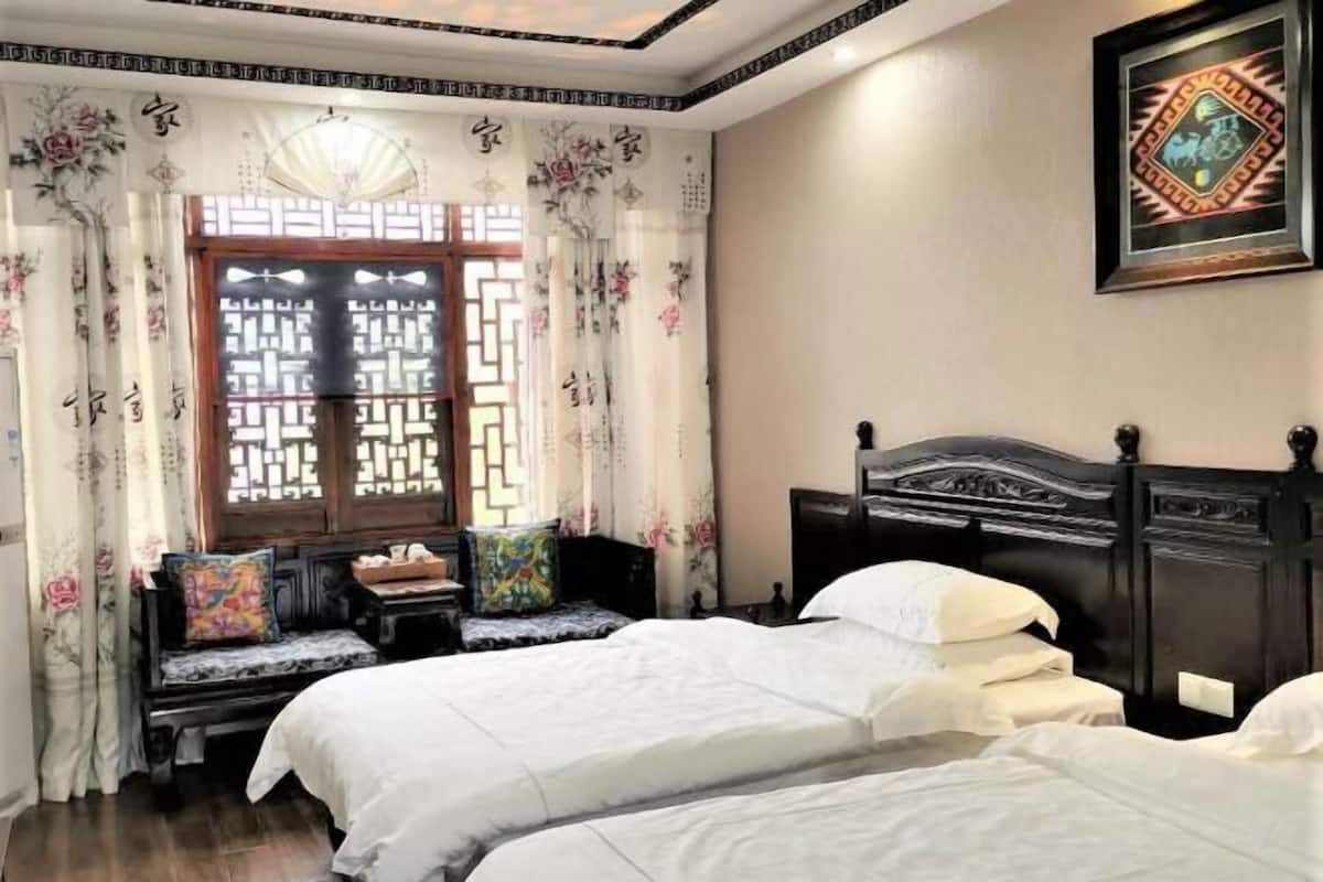 Une chambre de style traditionnel, dotée de deux lits, d’une tête de lit en bois, d’une fenêtre ornée d’un croisillon décoratif et d’un cadre photo fixé au mur.