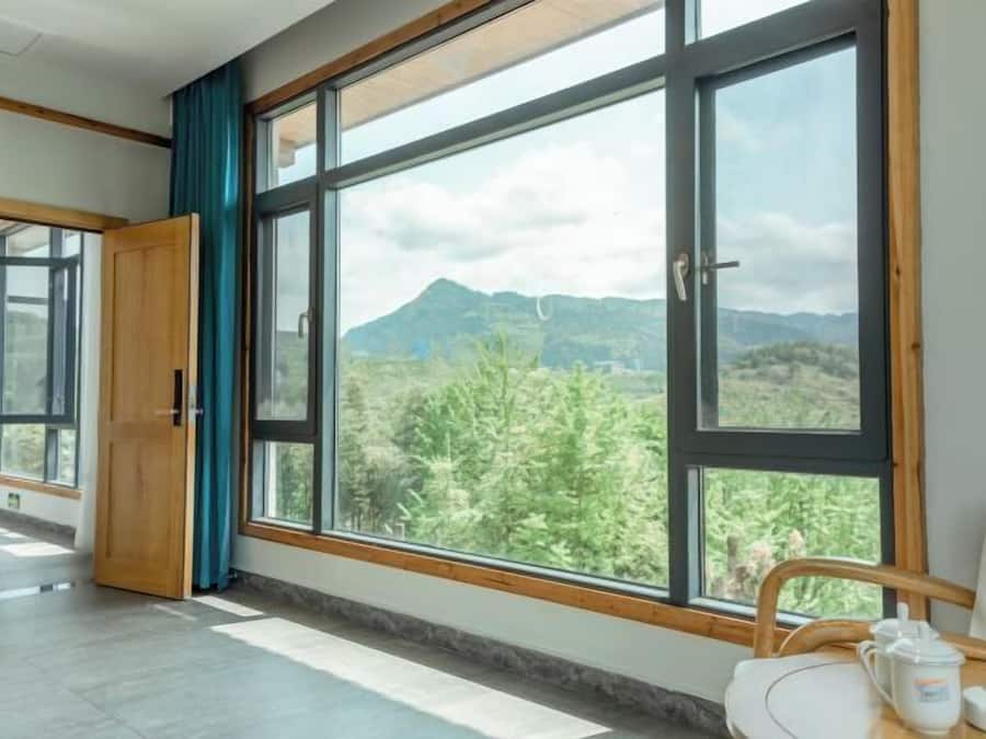 A room with a large window, a wooden door, and a table with a cup and saucer.