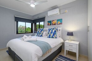 Une chambre à coucher comprenant un lit, une table de chevet, une lampe, un climatiseur et une fenêtre donnant sur un beau paysage.