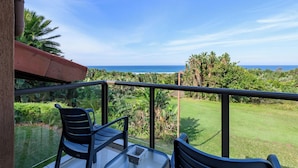 A balcony with two chairs and a table, overlooking a lush green landscape and the ocean. - San Lameer Villa 3706 (Southbroom)