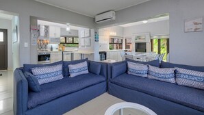 A modern living room with a sofa set, a dining area, and a kitchen. - San Lameer Villa 3706 (Southbroom)