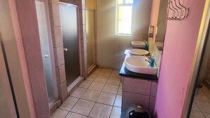 Een badkamer met twee wastafels, een raam en een douchehoek.