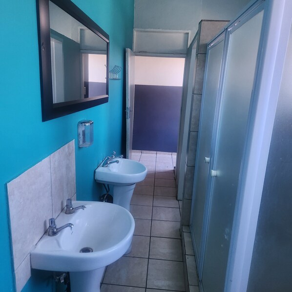 Une salle de bain avec deux lavabos, un miroir et un espace douche.