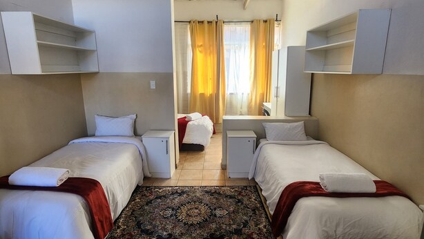 Een hotelkamer met twee enkele bedden, een klein bureau, een kledingkast en een badkamer.