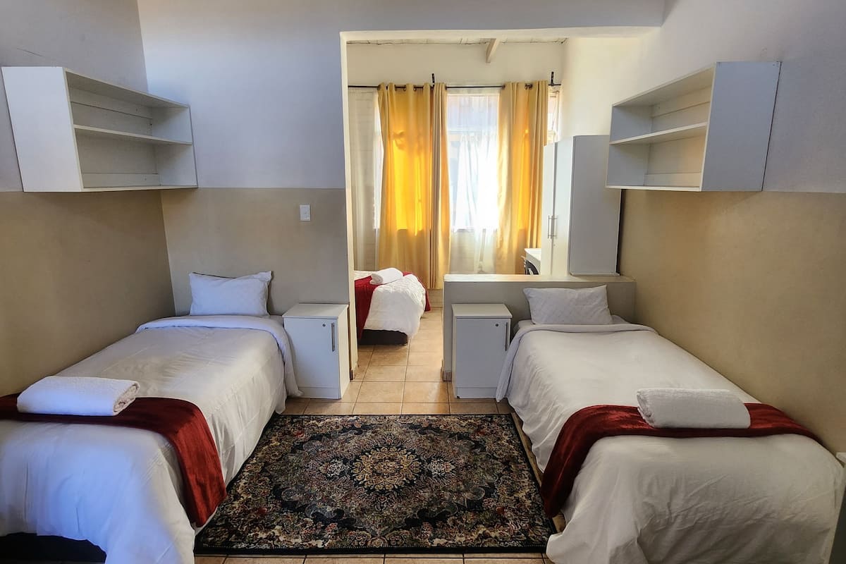 Een hotelkamer met twee enkele bedden, een klein bureau, een kledingkast en een badkamer.