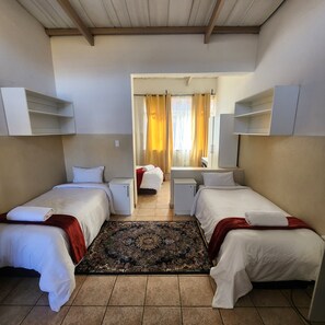 Une chambre d’hôtel avec deux lits simples, un petit bureau, une armoire et une salle de bain.