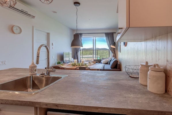 A kitchen with a sink, a dining area with a table and chairs, and a view through a window. - Sommet de la basse-ville / Downtown (Ville de Québec)