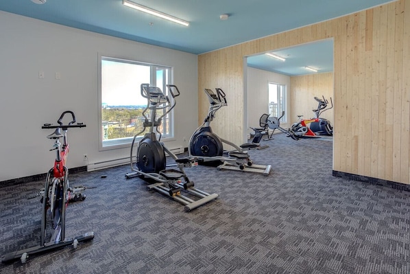 A gym with cardio machines, weight stations, and a view of the city. - Sommet de la basse-ville / Downtown (Ville de Québec)