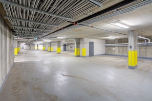 A multi-level parking garage with concrete floors and walls, yellow safety posts, and visible structural beams and pipes. - Sommet de la basse-ville / Downtown (Ville de Québec)