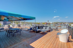 Eine Dachterrasse mit Sitzgelegenheiten im Freien, einem überdachten Bereich und Blick auf die Stadtlandschaft.