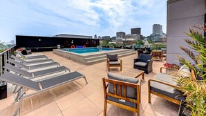 A rooftop pool area with lounge chairs, a pool, and a cityscape view. - Le Jules-Rooftop Pool (Québec)