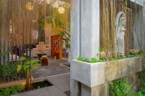 A traditional interior with a stone statue, a wooden door, and a hanging plant.