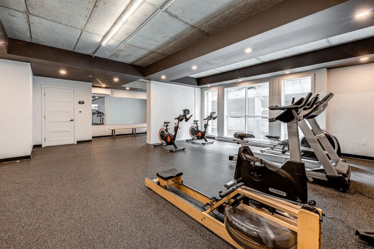 A gym with cardio machines, a rowing machine, and a bench.