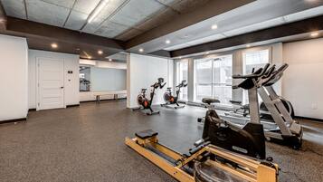 A gym with cardio machines, a rowing machine, and a bench.