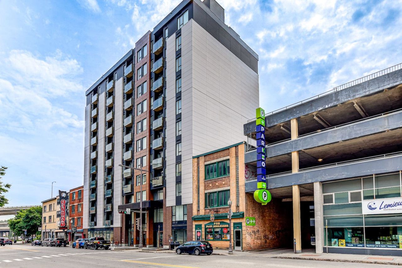 A multi-story building with a parking garage entrance, a pub, and a storefront with a sign.