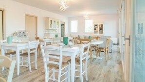 A bright, spacious kitchen with white cabinetry, wooden chairs, and a dining table set for four. - I Campi Wine Relais (Lazise)