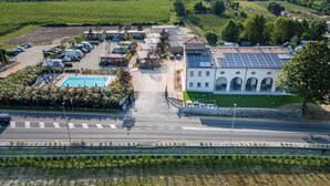An aerial view of a hotel with a swimming pool, solar panels, and a parking lot. - I Campi Wine Relais (Lazise)