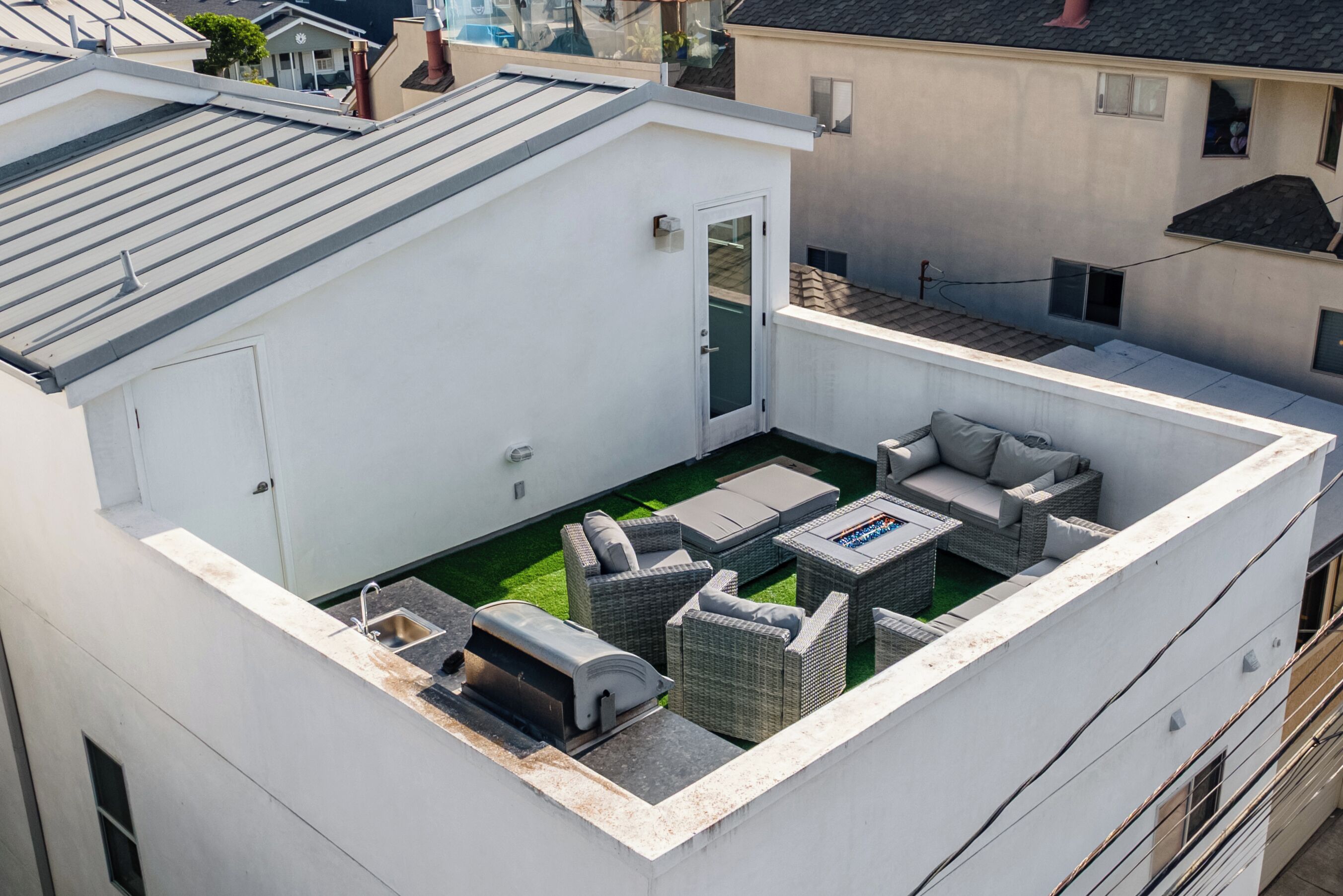 Une terrasse sur le toit, aménagée avec du mobilier d’extérieur, un barbecue et un petit espace jardin.