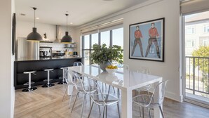 A modern kitchen with a white island, bar stools, and a dining area with a white table and chairs. - The Carter by AvantStay | 5th Floor, 15 Bedrooms (Nashville)