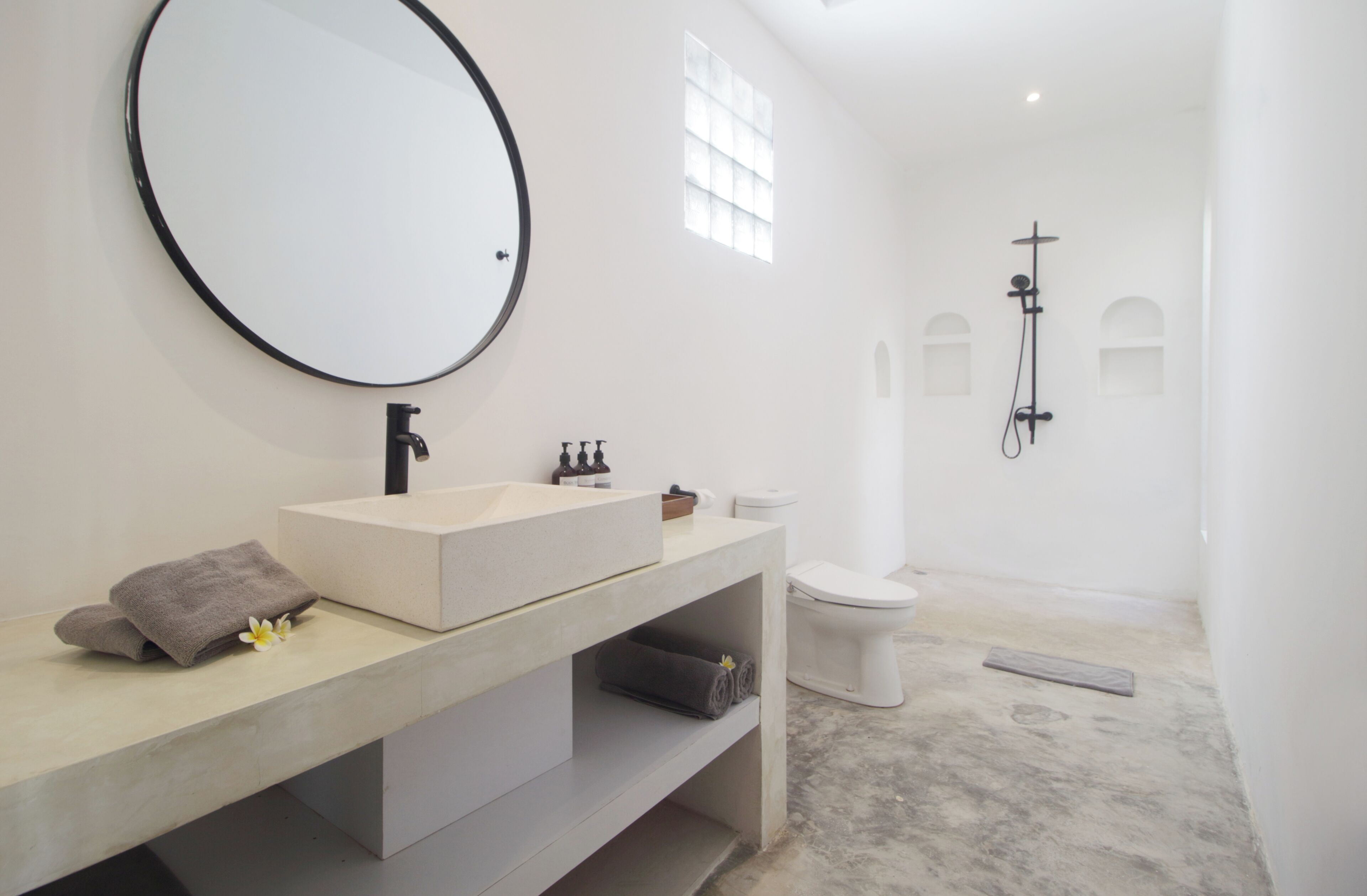 A modern bathroom with a large mirror, a sink, a toilet, and a shower.
