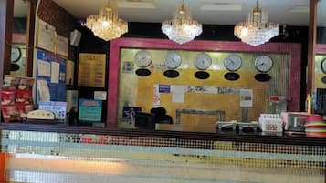 A reception area with a tiled wall, clocks, and a counter with various items.