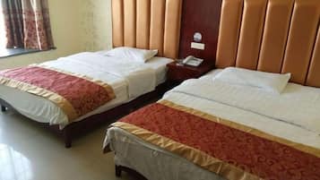 Two single beds with headboards, a bedside table with a phone, and a window with curtains.