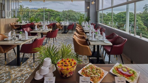 Un restaurante con mesas listas para comer, un ventanal que ofrece vistas a zonas verdes y un ventilador de techo.