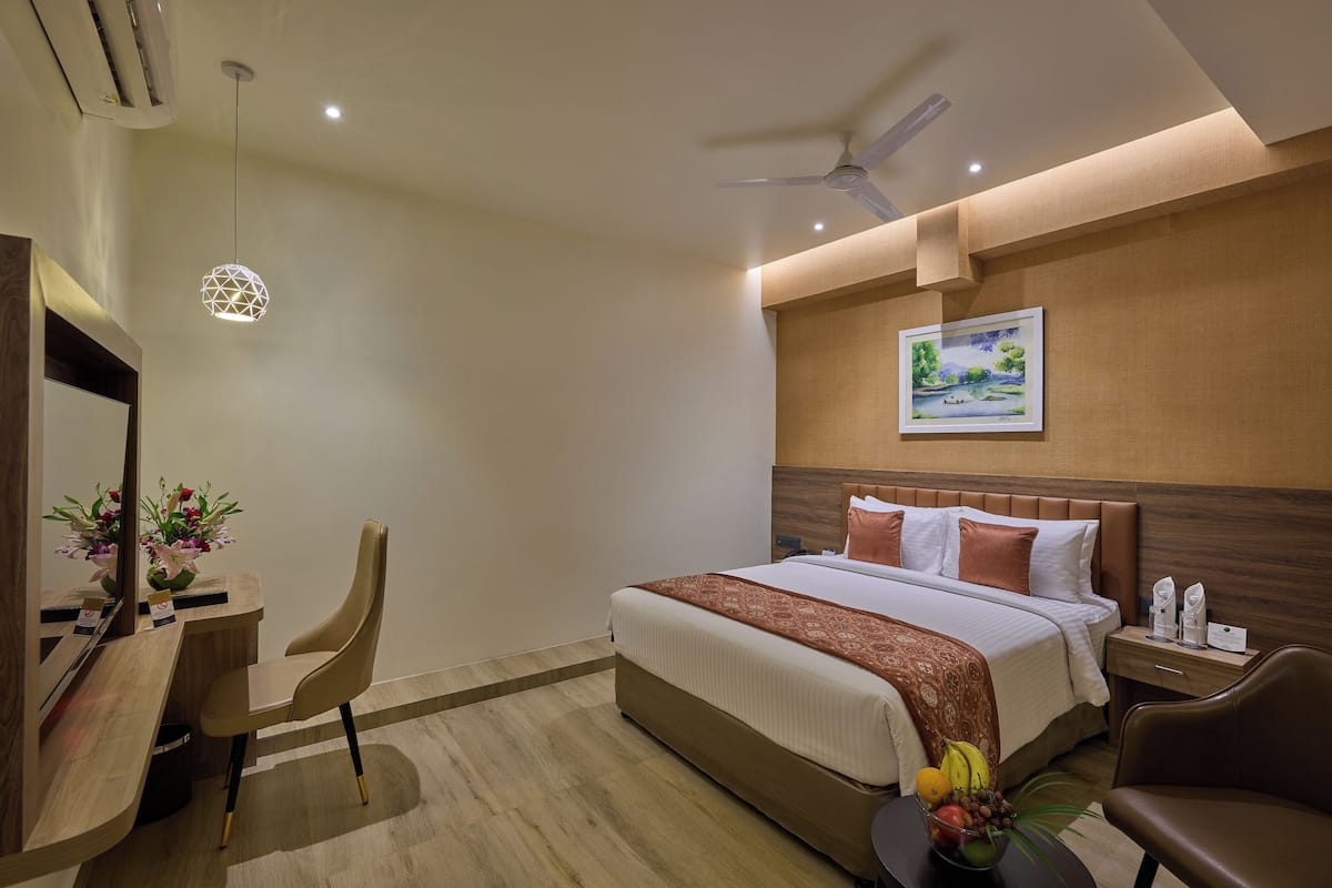 Een hotelkamer met een bed, bureau, stoel en een schilderij aan de muur.