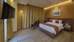 Habitación de hotel con una cama grande, televisión de pantalla plana, un escritorio con una silla y un cuadro en la pared.