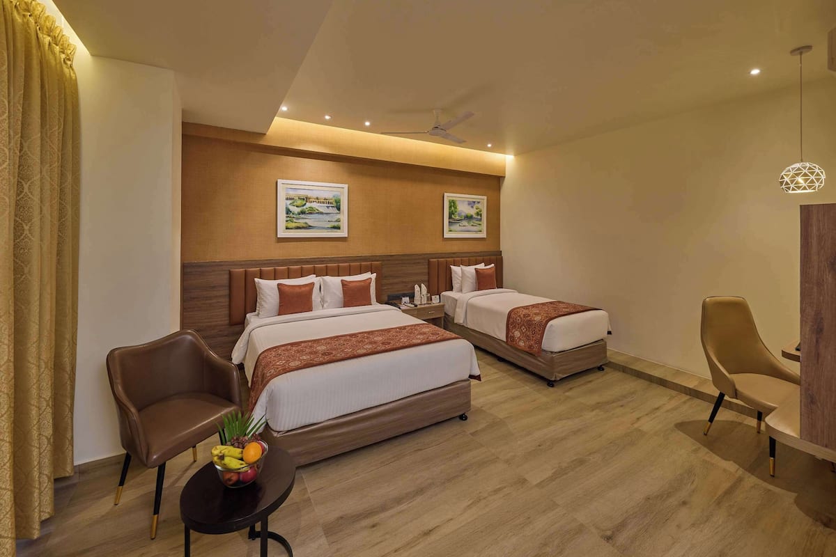 Een hotelkamer met twee bedden, een bureau, een stoel en een kleine tafel met fruit.