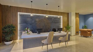 Un área de recepción con diseño moderno, que incluye un mostrador de recepción, dos sillas y una pared decorativa.
