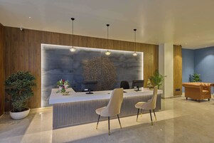 Un espace d’accueil au design moderne, comprenant un comptoir de réception, deux chaises et un mur décoratif.