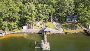 A lakeside property with a dock, a small shed, and a house surrounded by dense forest. - The Overlook at Langford - Private dock with SUPs, Kayaks, and Ping Pong (Leesville)