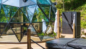 A geodesic dome structure with a wooden deck and a sauna area. - Allure Muskoka Glass Dome (Huntsville)
