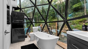 A modern bathroom with a freestanding bathtub, a toilet, and a shower area. - Allure Muskoka Glass Dome (Huntsville)