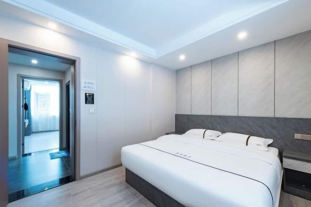 Une chambre d’hôtel moderne dotée d’un grand lit, d’une armoire intégrée et d’une porte donnant sur un couloir.