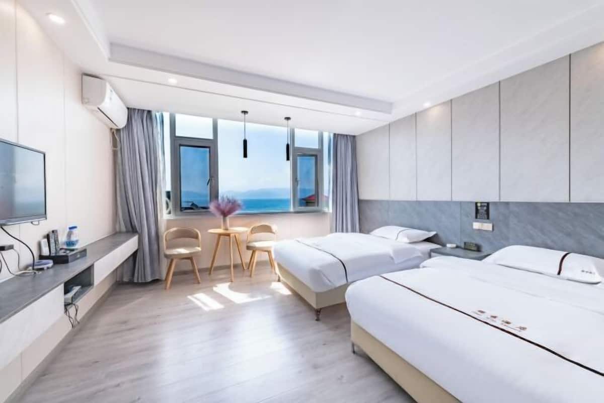 Une chambre d’hôtel moderne équipée d’un lit, d’une table de chevet, d’une télévision et offrant une vue sur la mer.