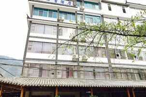 Um edifício de vários andares com estilo arquitetônico tradicional, com telhado em telhas e várias janelas.