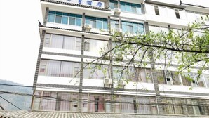 A multi-story hotel with a traditional architectural style, featuring a tiled roof and multiple balconies.