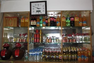 Loja de bebidas com prateleiras repletas de garrafas e caixas diversas.