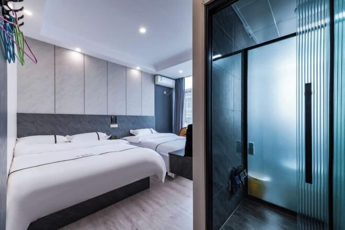 Une chambre d’hôtel moderne avec deux lits, une cloison en verre et une vue sur la ville.