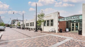Eine Straße mit Gebäuden, auf denen 'The Garage', eine Coca-Cola Abfüllanlage und ein Fahrrad vor der Tür stehen.