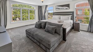 Een slaapkamer met een bed, een bank, een plafondventilator en grote ramen.