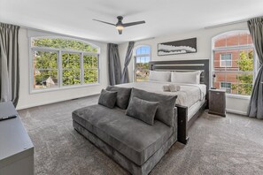 Ein Schlafzimmer mit Bett, Sofa, Deckenventilator und großen Fenstern.