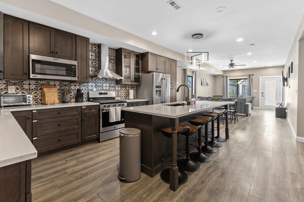 A modern kitchen with dark wood cabinets, stainless steel appliances, and a central island with bar stools.