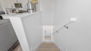 A modern kitchen with white cabinetry, a stainless steel refrigerator, and a built-in microwave. - Indy Carriage House in Downtown (Indianapolis)
