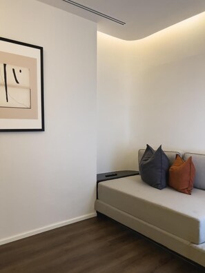 Ein schlichter Raum mit einer Couch, einem gerahmten Kunstwerk und einer Deckenleuchte.