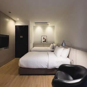 Ein modernes Hotelzimmer mit einem großen Bett, einem Schreibtisch, einem Sessel und einem Flachbildfernseher.
